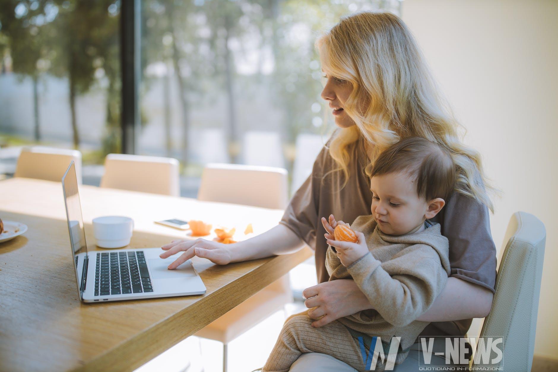 woman carrying her baby and working on a laptop